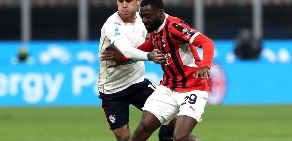 AC Milan player challenging Cagliari opponent