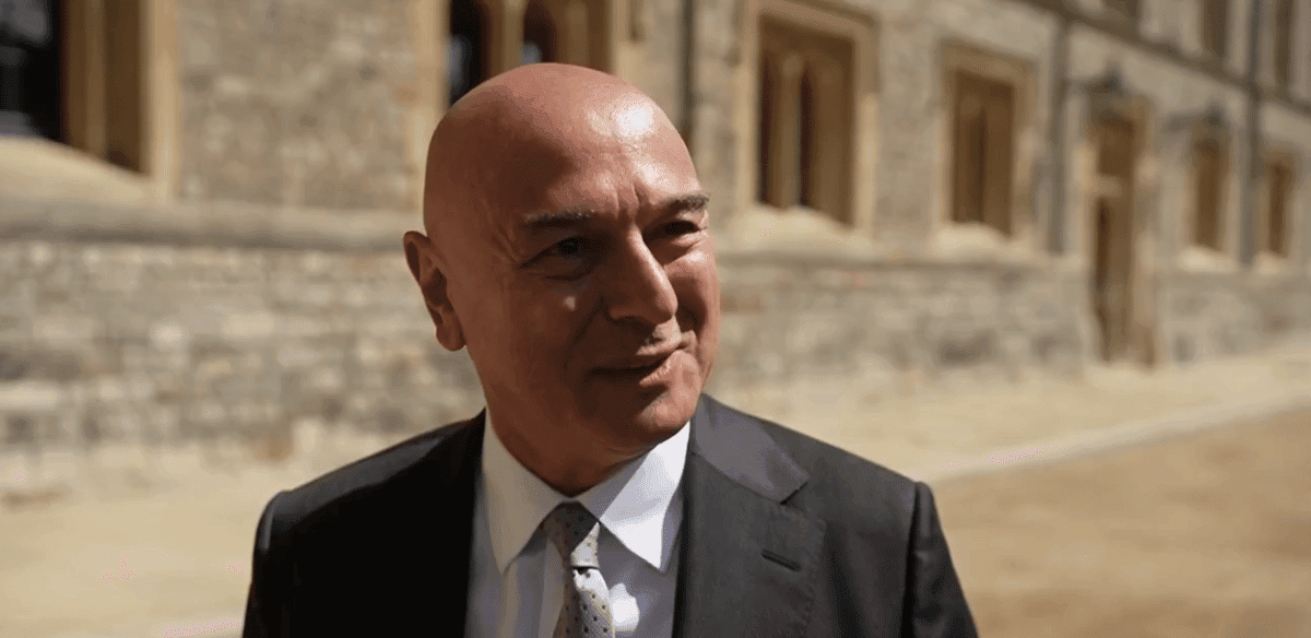 Man in suit smiling outdoors near stone building