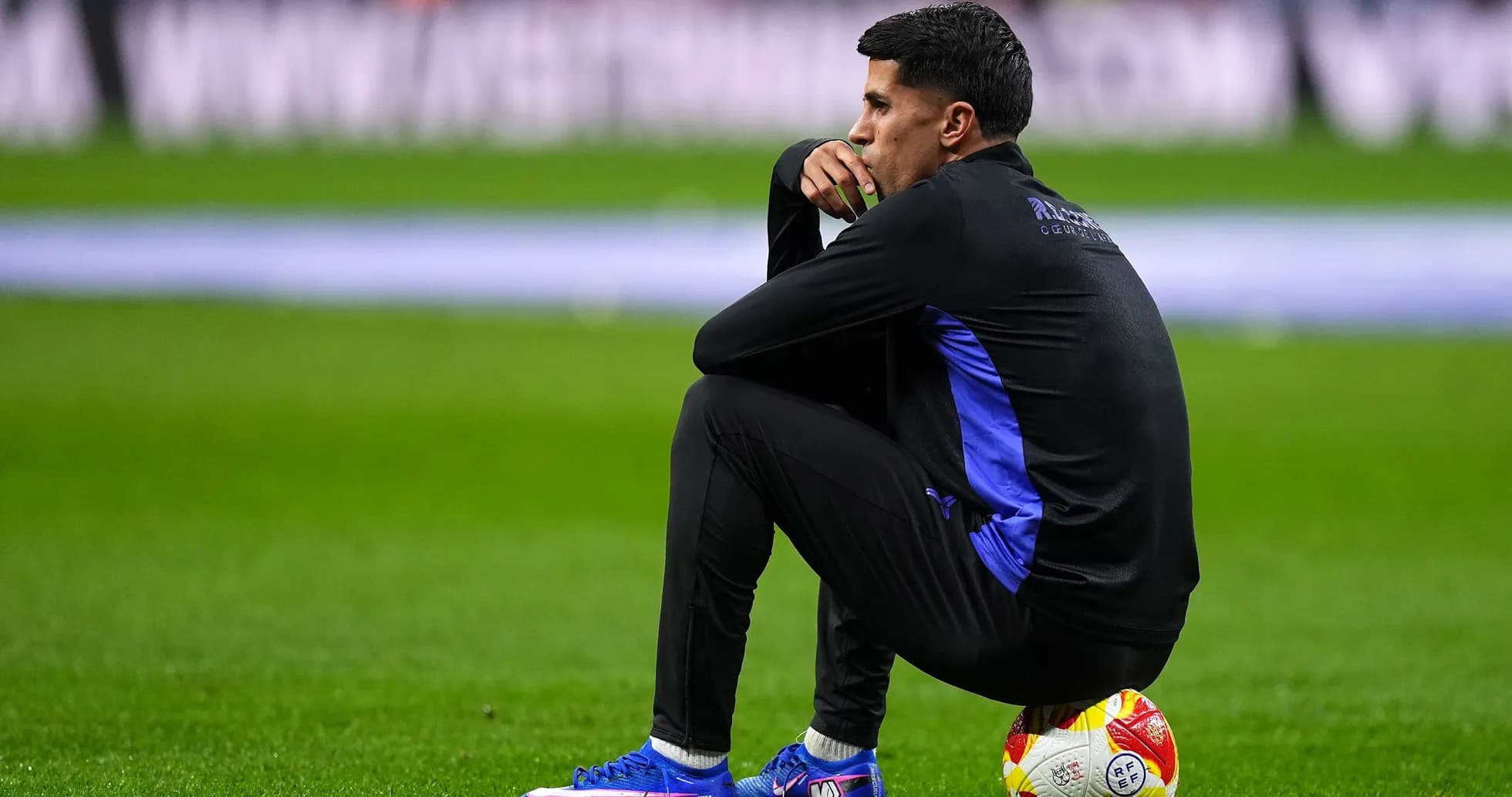 Coach sitting on the pitch next to a ball