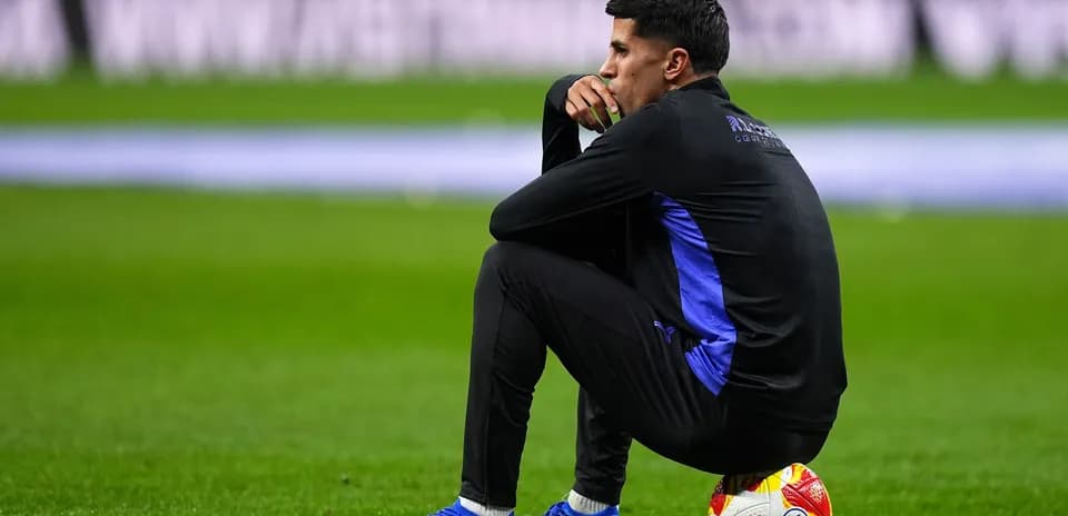 Coach sitting on the pitch next to a ball