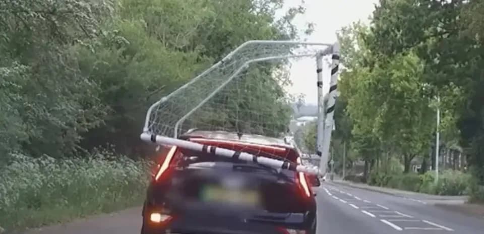 Car transporting a soccer goal on its roof