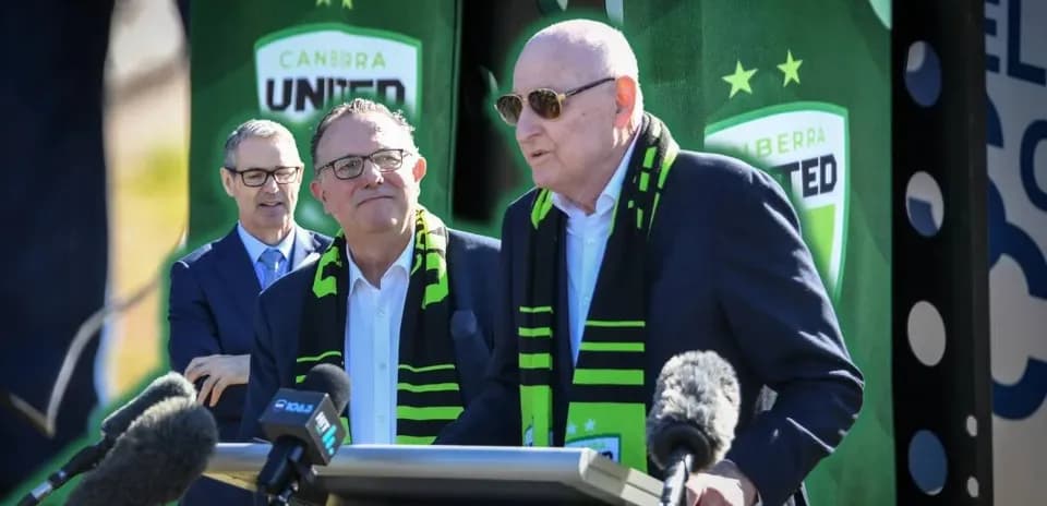 Officials at Canberra United press conference with scarves
