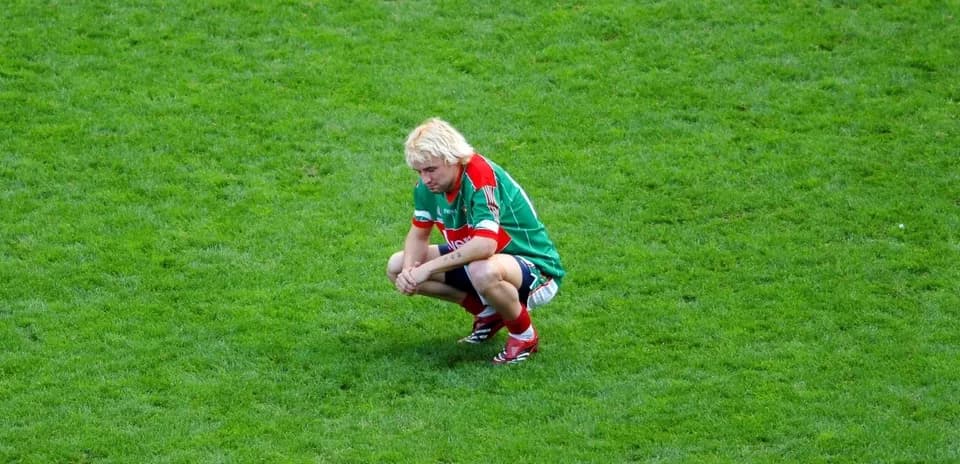 Player squatting on grass field after play