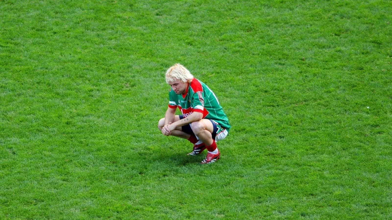 Player squatting on grass field after play