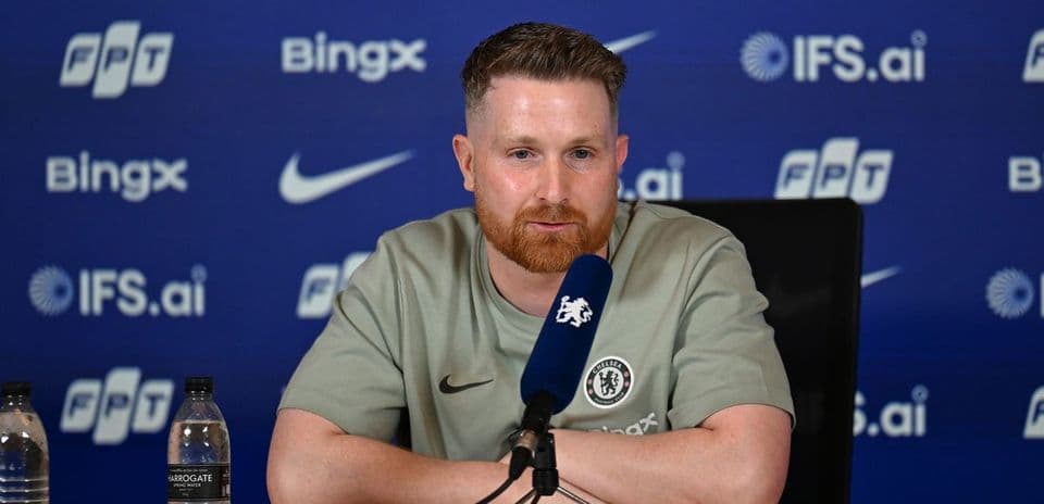 Man speaking at press conference with Chelsea logo