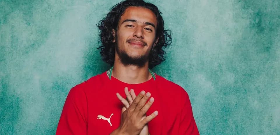 Player posing in red jersey against green backdrop