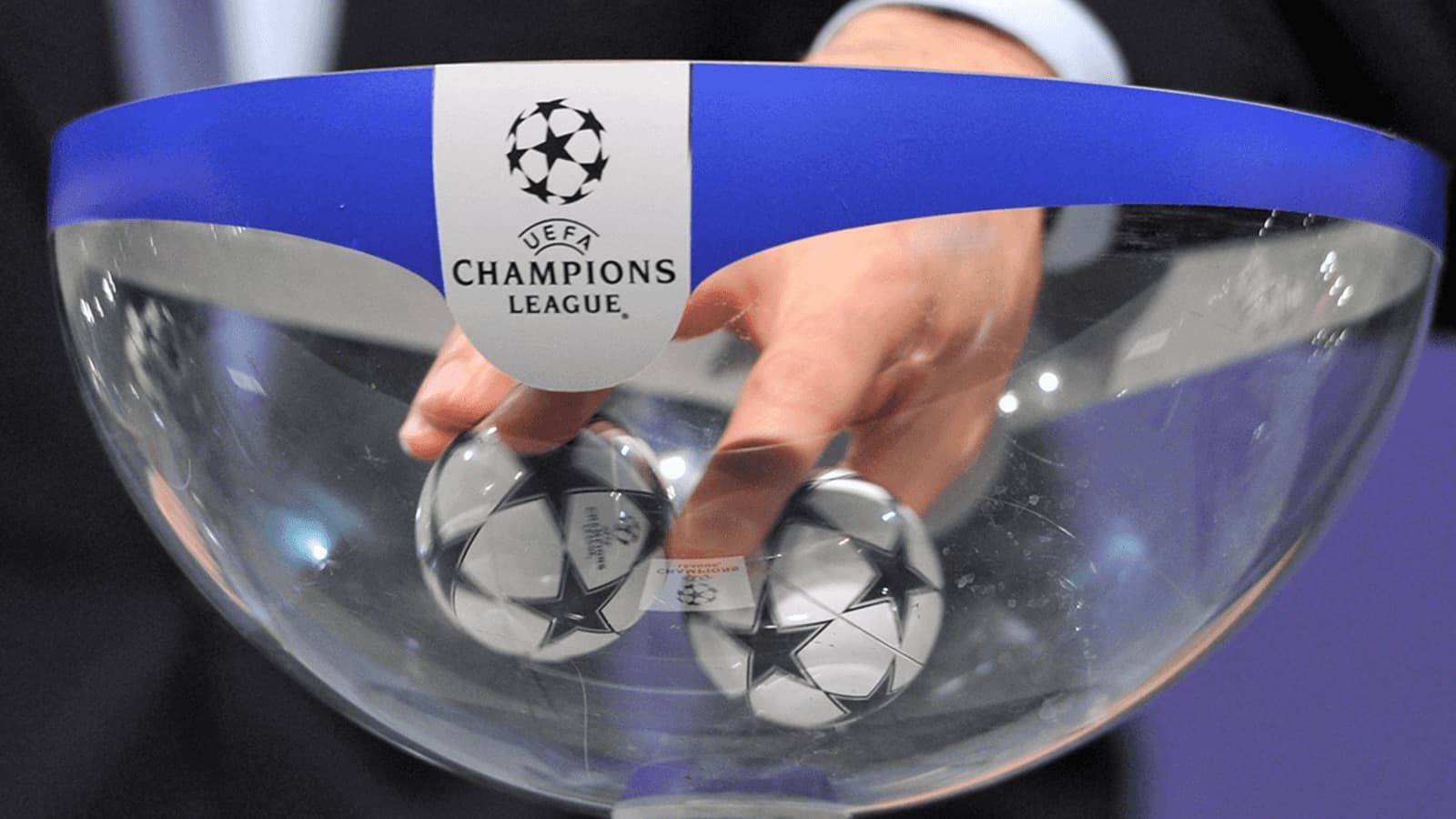 Hand reaching into UEFA Champions League draw bowl