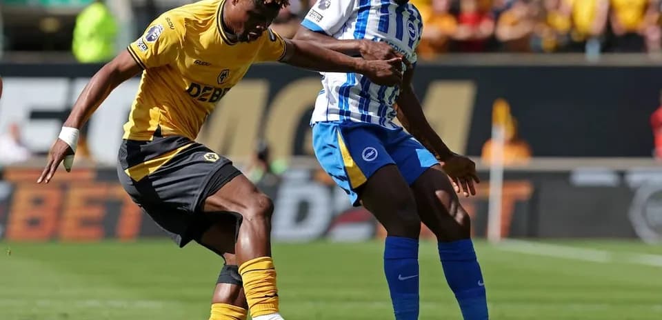 Brighton player challenging Wolves player for the ball