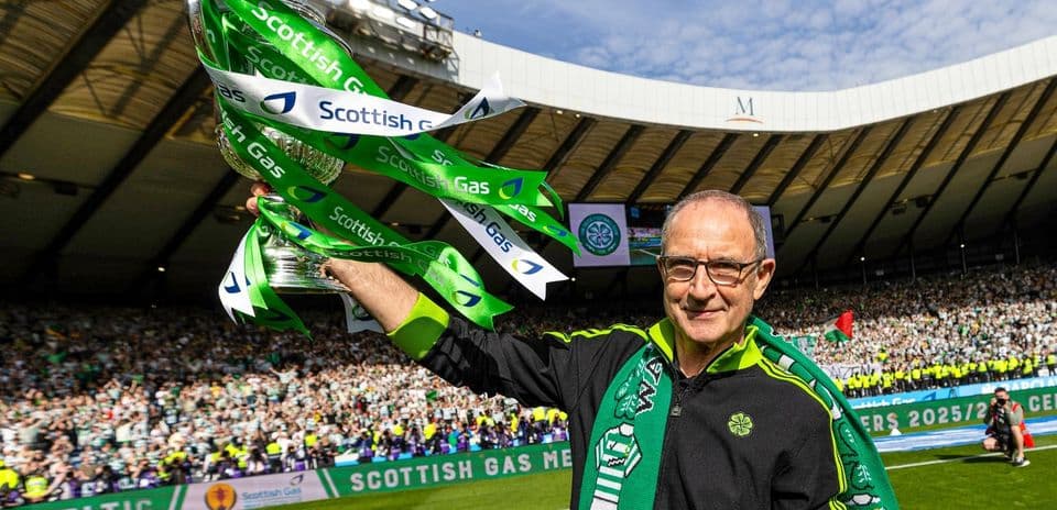 Person celebrating with trophy and green ribbons