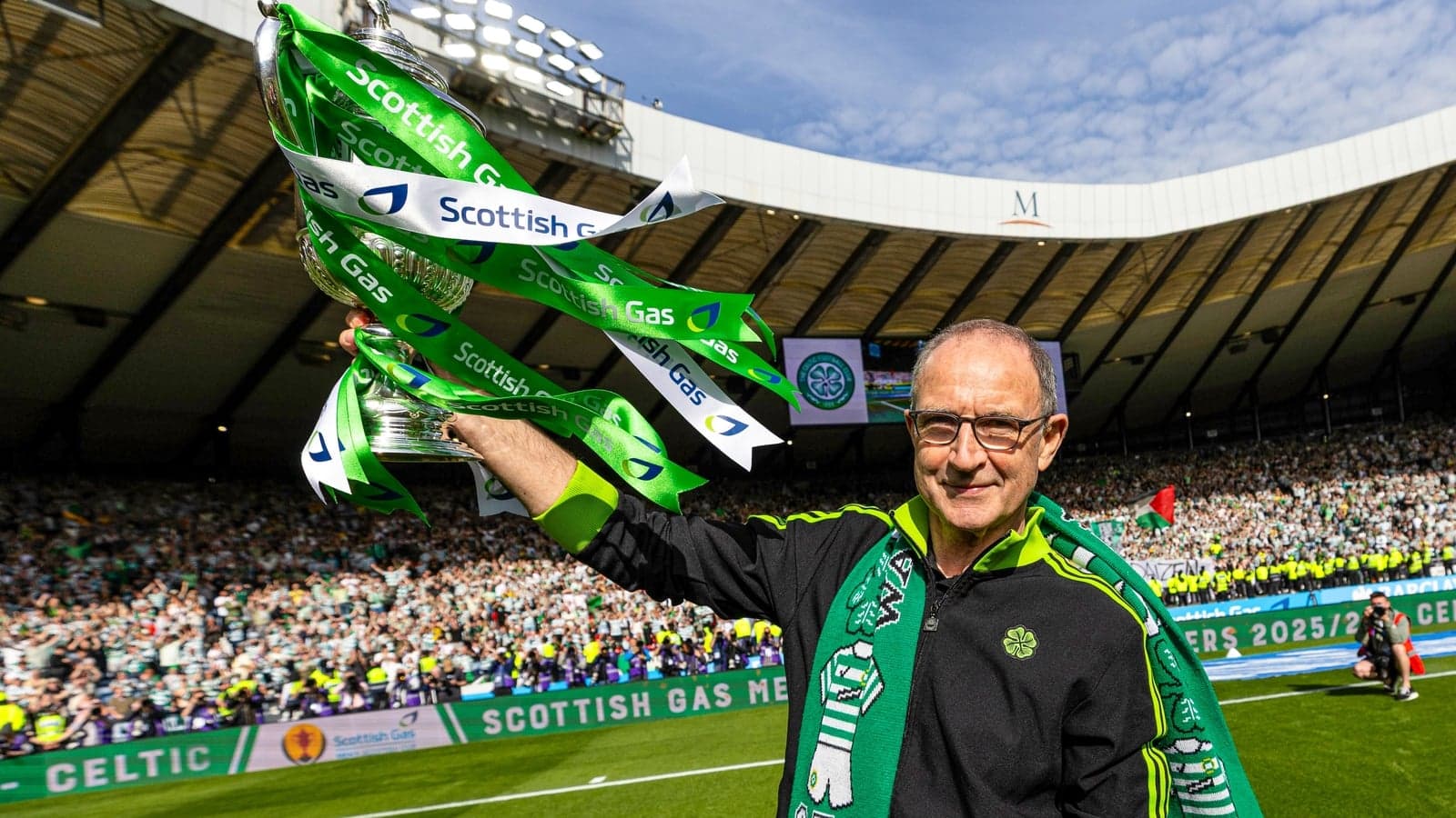Person celebrating with trophy and green ribbons