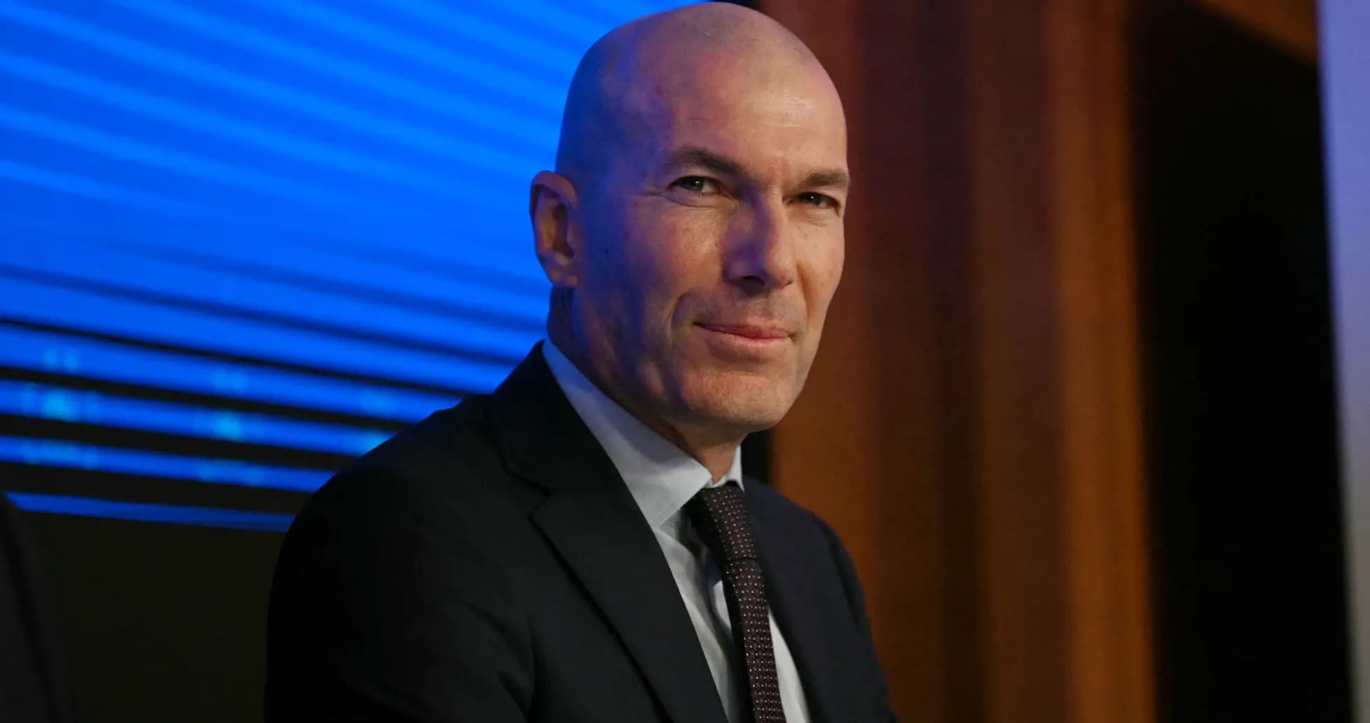 Man in suit seated at a press conference