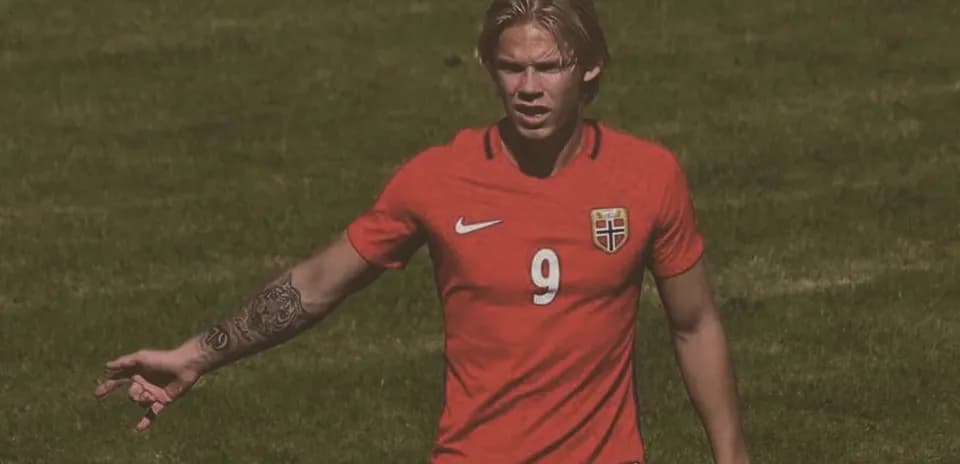 Player in red jersey gesturing on football field
