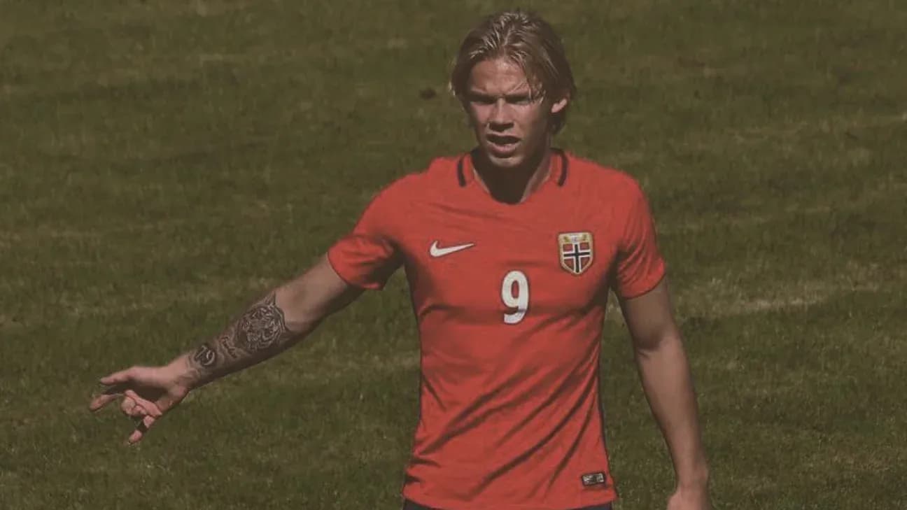 Player in red jersey gesturing on football field