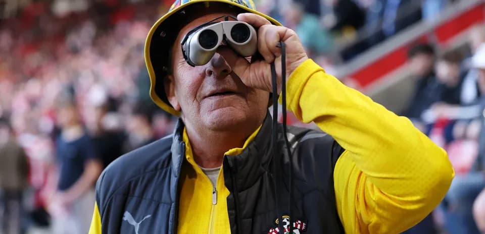 Fan wearing binoculars and Southampton gear at match