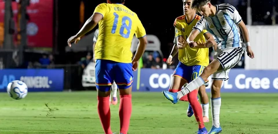 Argentinian player kicking ball past defenders