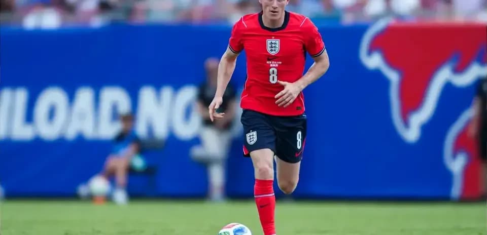 Player in red uniform dribbling soccer ball on field