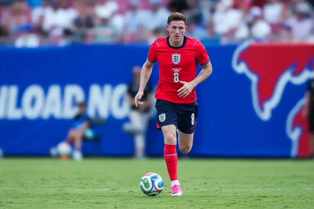 Player in red uniform dribbling soccer ball on field