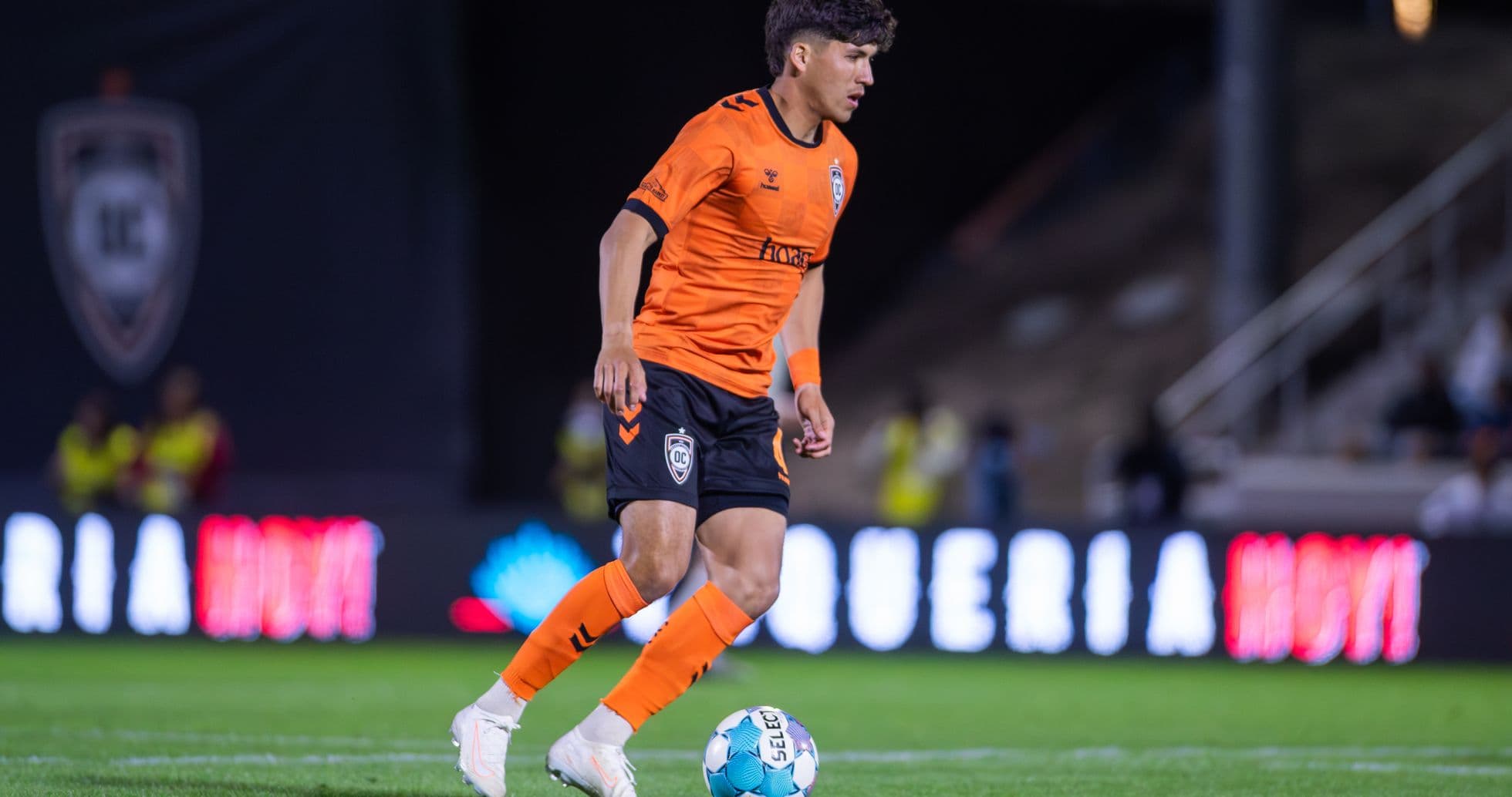 Player in orange kit dribbling the ball