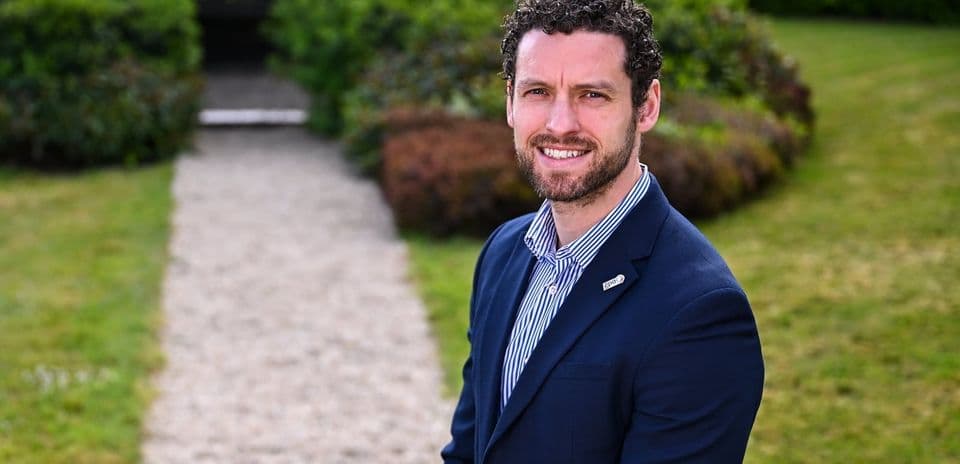 Man in suit smiling in garden setting