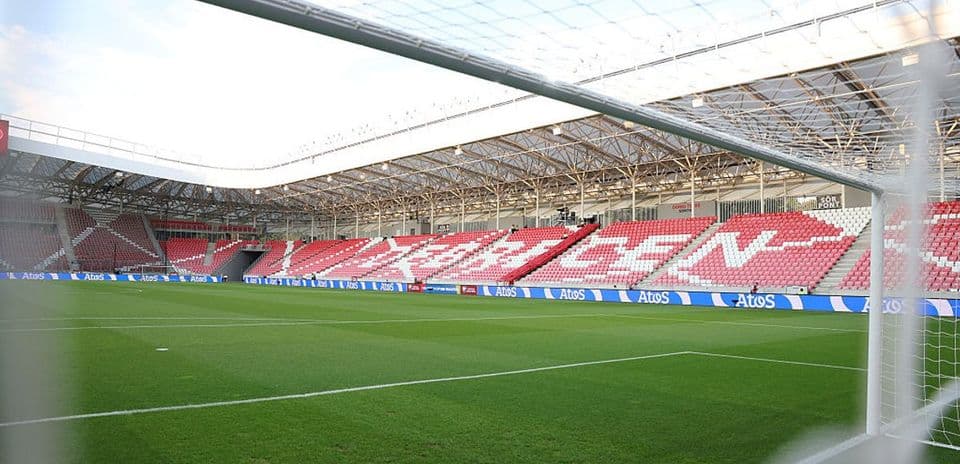 View of empty stadium with green pitch and seating