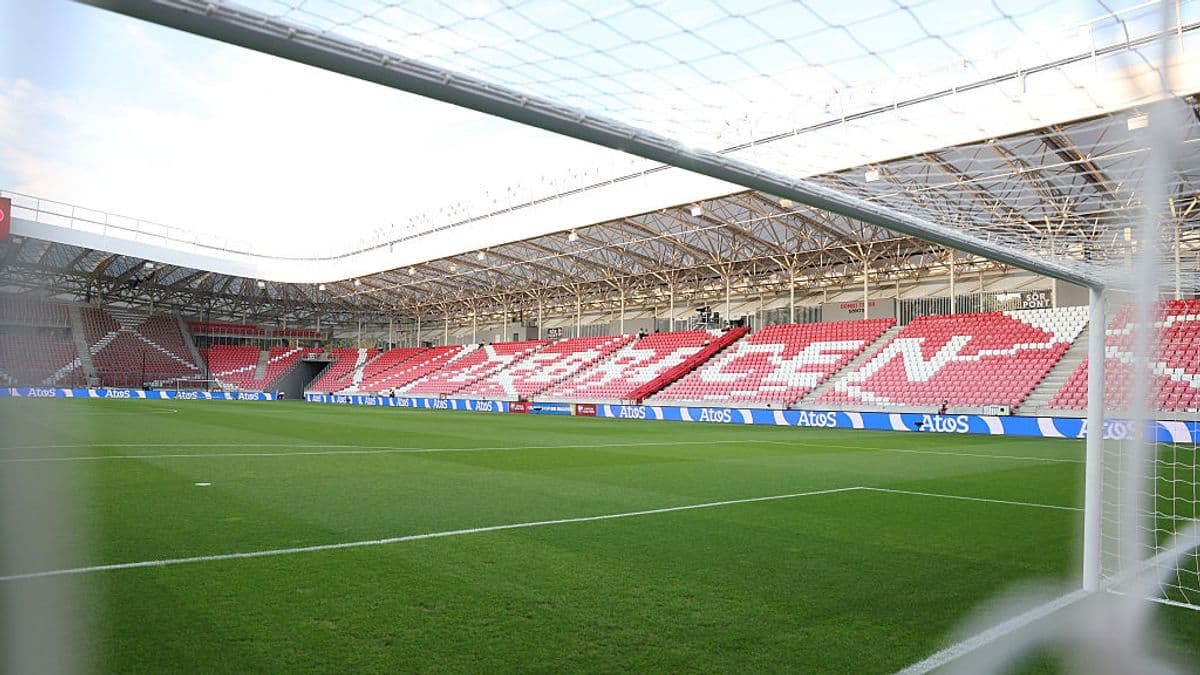 View of empty stadium with green pitch and seating