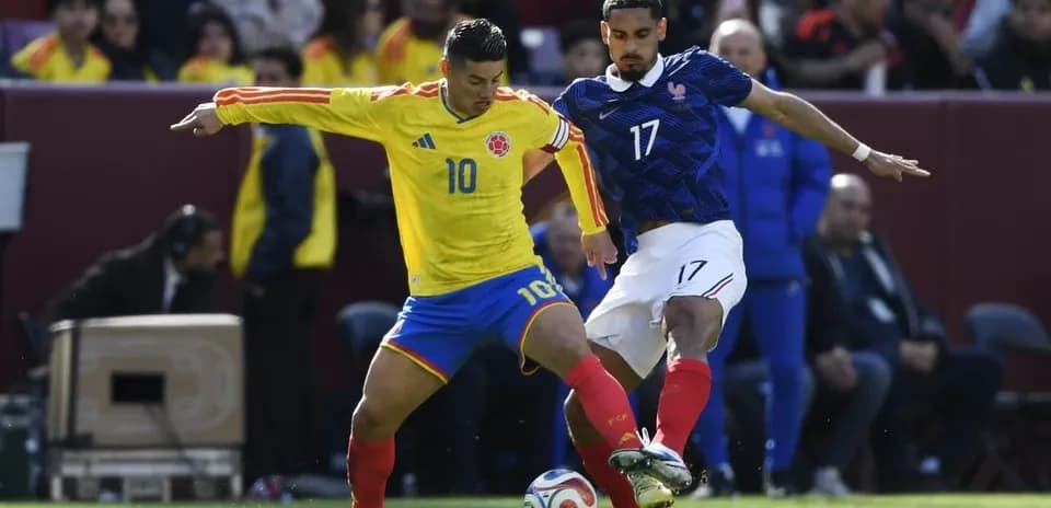 Colombian player dribbling past French defender during match