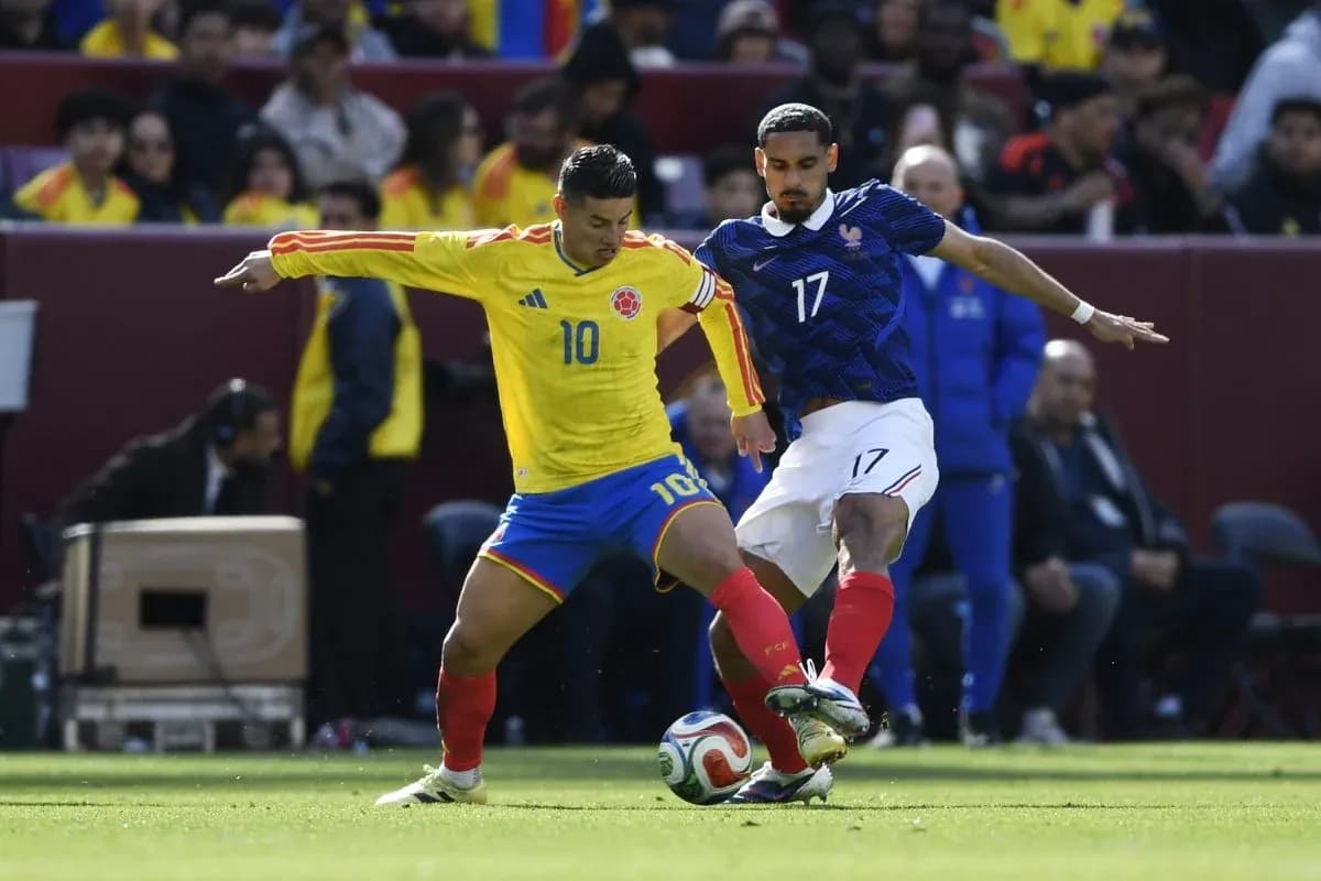 Colombian player dribbling past French defender during match
