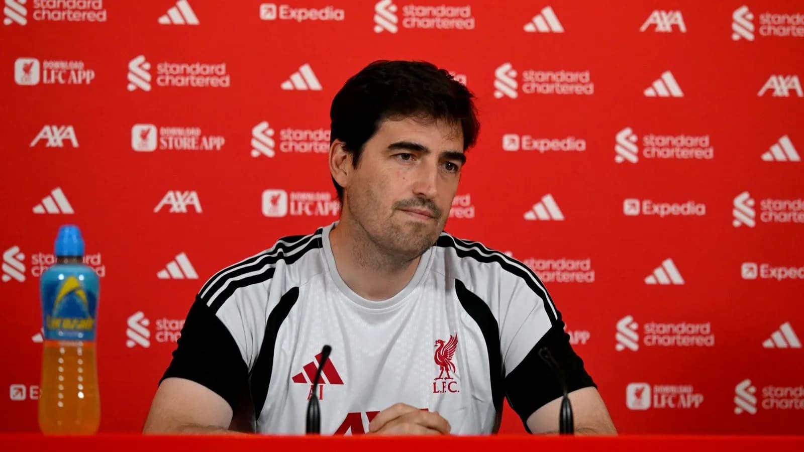 Coach at Liverpool FC press conference with backdrop