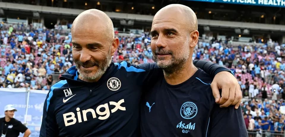 Two football coaches smiling together after a match