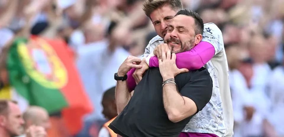 Two coaches celebrating a goal with an embrace