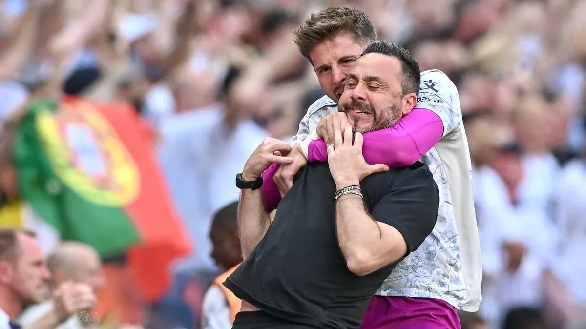 Two coaches celebrating a goal with an embrace
