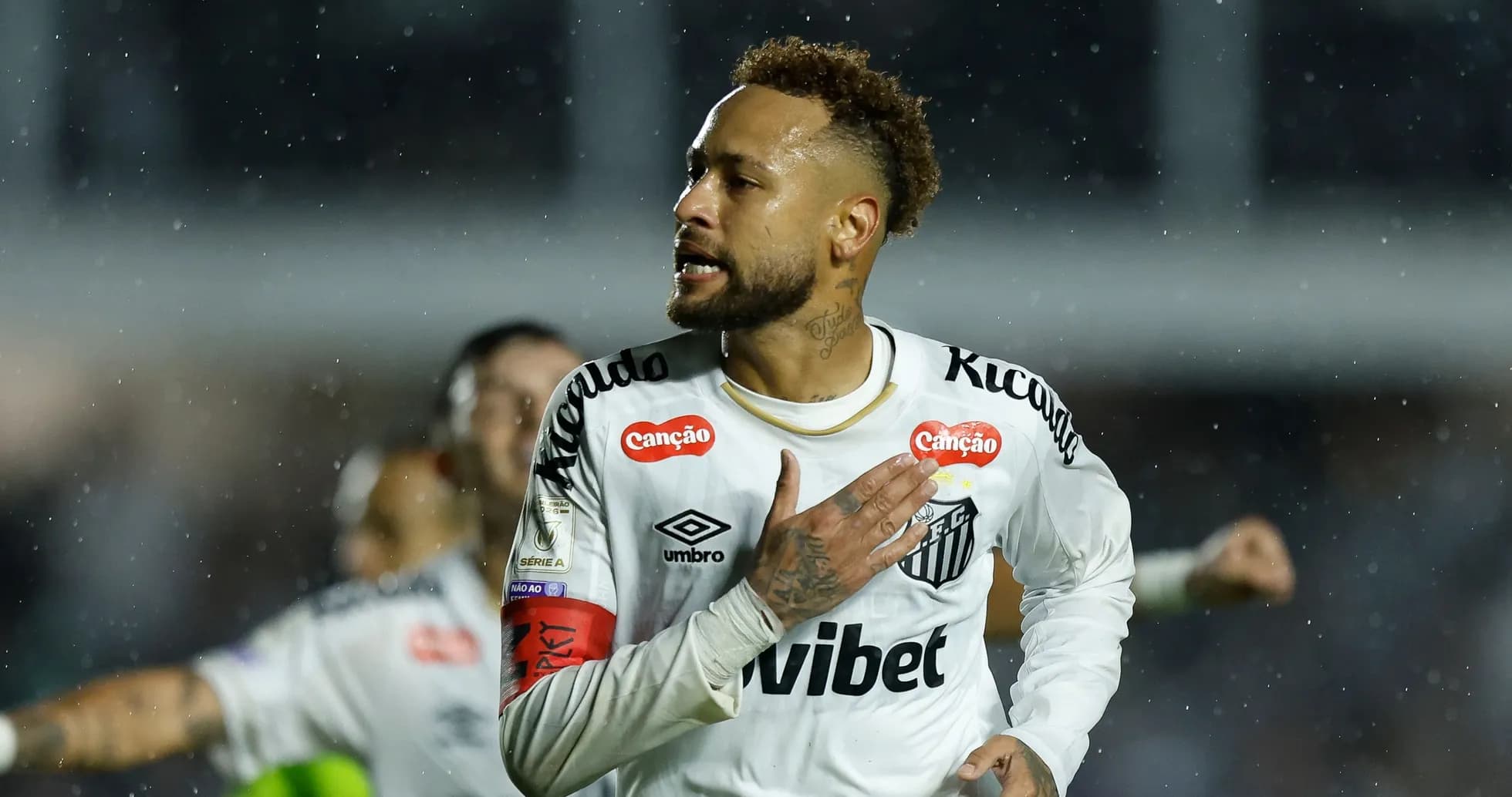 Player celebrating a goal in a rainy match