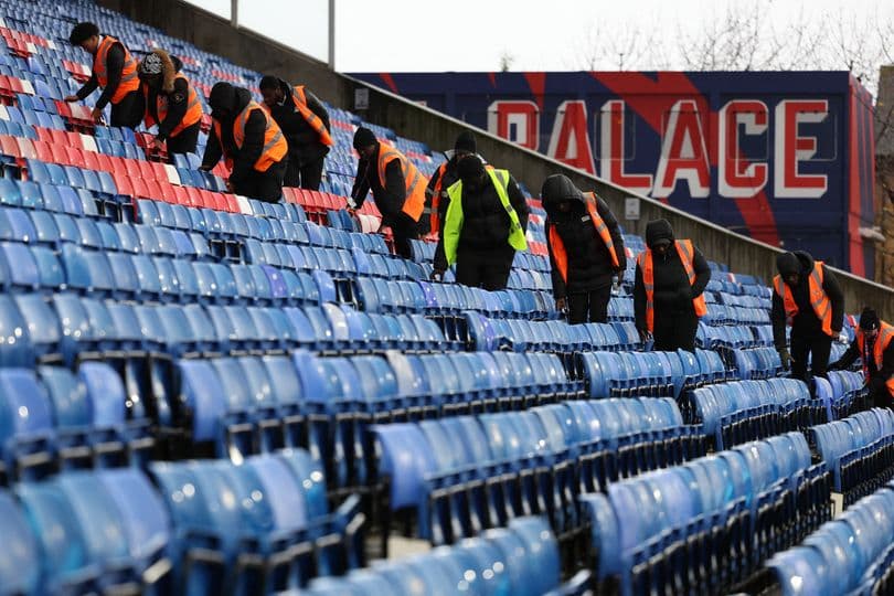 Staff cleaning seats in stadium stands before event