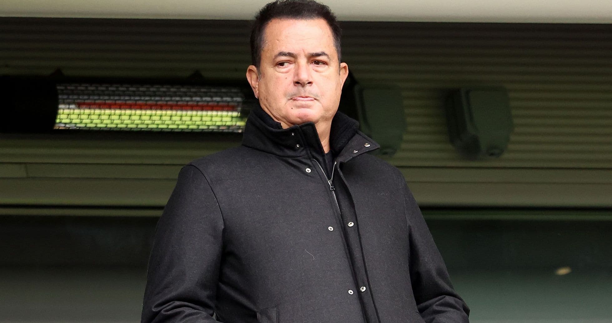 Person standing in a stadium wearing a black coat