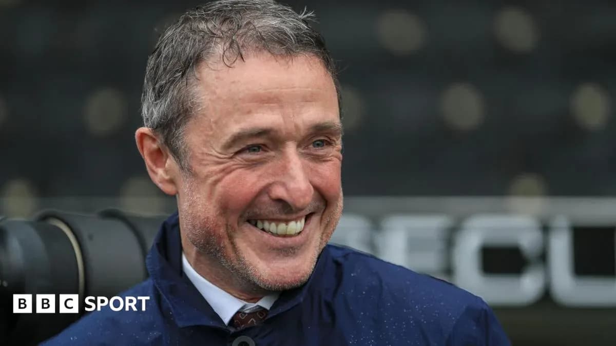 Man smiling in a raincoat at a stadium