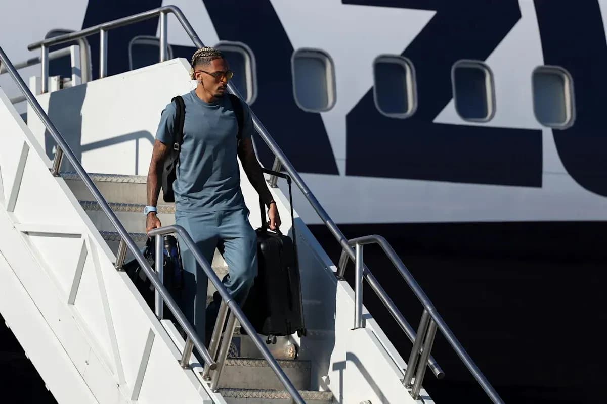 Player exiting airplane with suitcase at airport