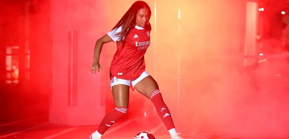 Player in Arsenal kit preparing to kick soccer ball