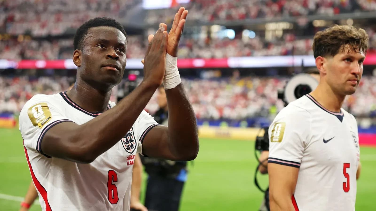 Two England players applauding fans after match