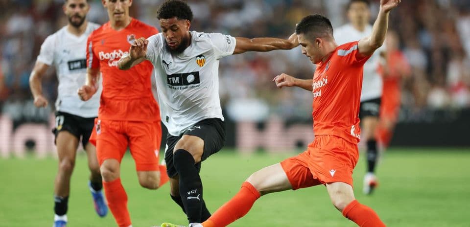 Real Sociedad player challenges Valencia opponent for the ball