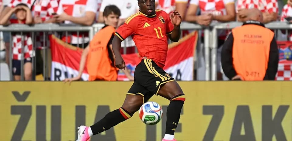Player in red jersey dribbling soccer ball during match