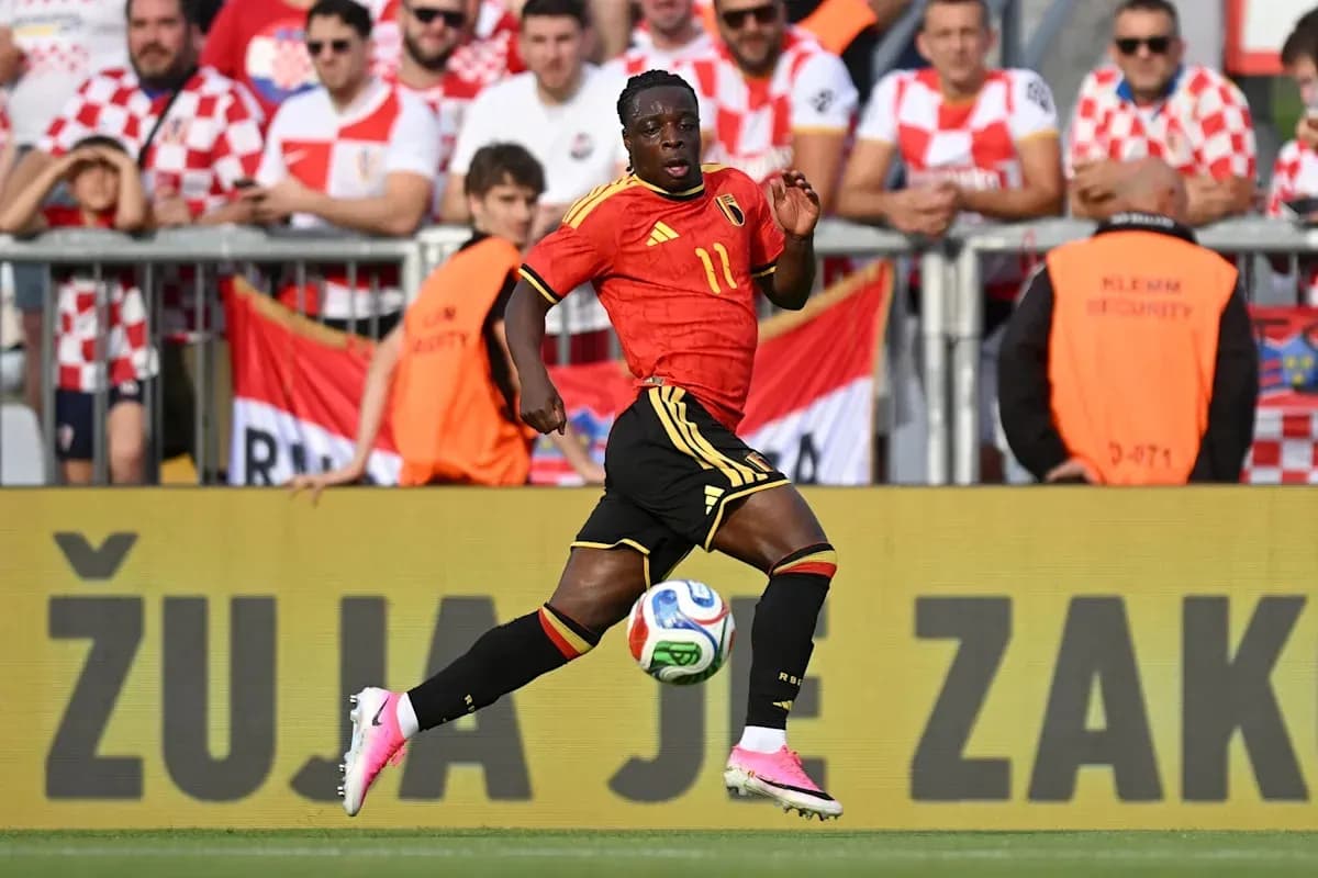 Player in red jersey dribbling soccer ball during match