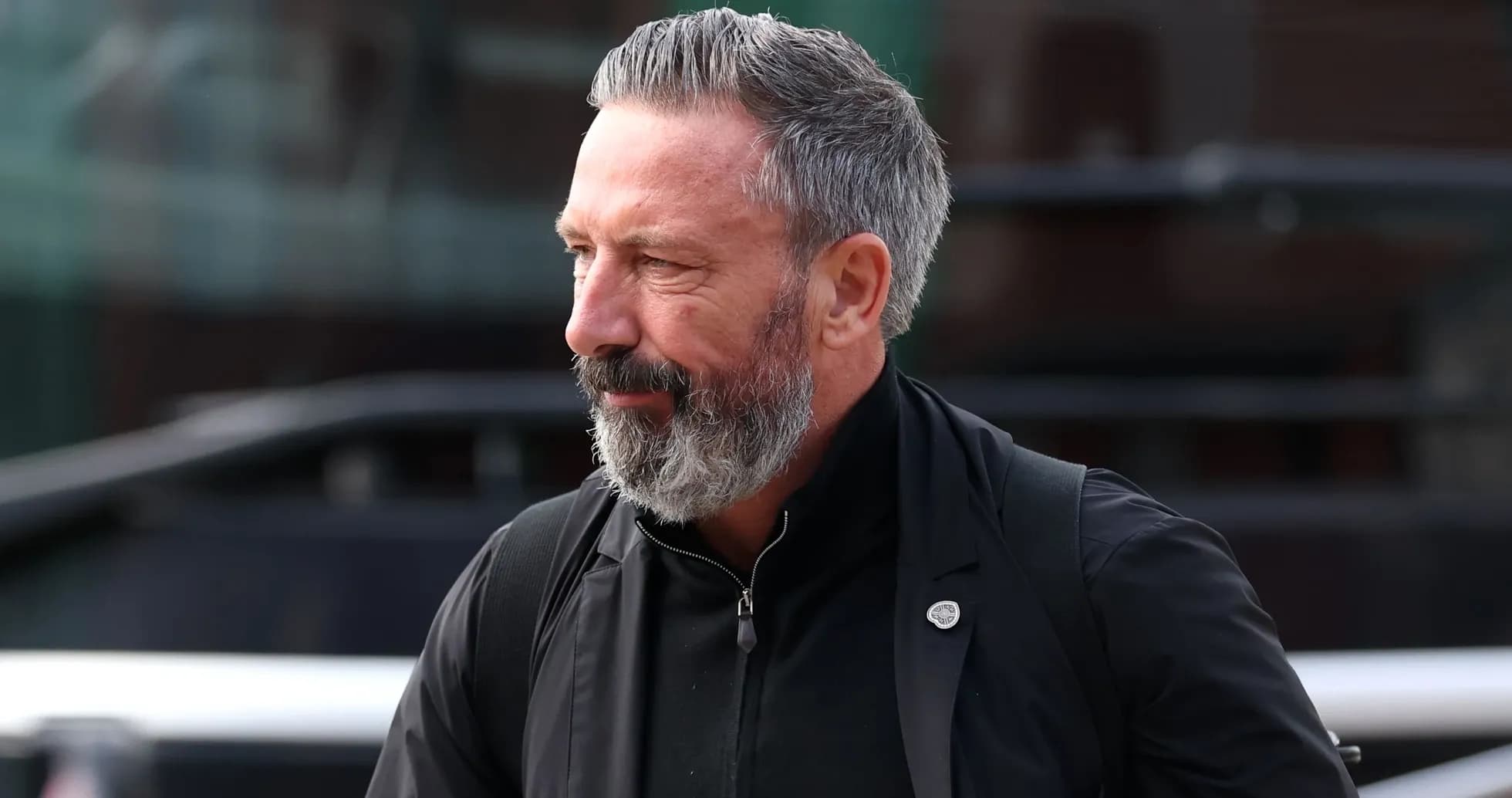 Man with beard walking outside near vehicle