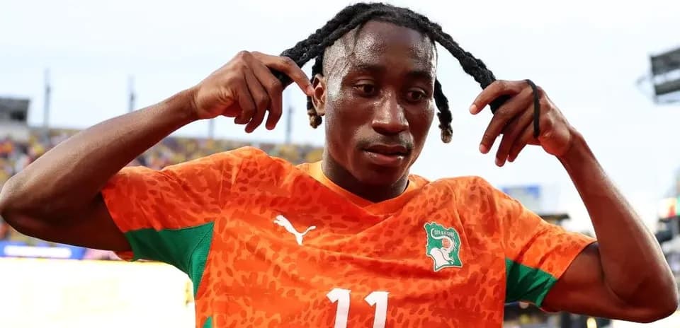 Player adjusting hair in orange football jersey
