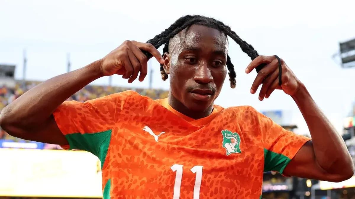 Player adjusting hair in orange football jersey