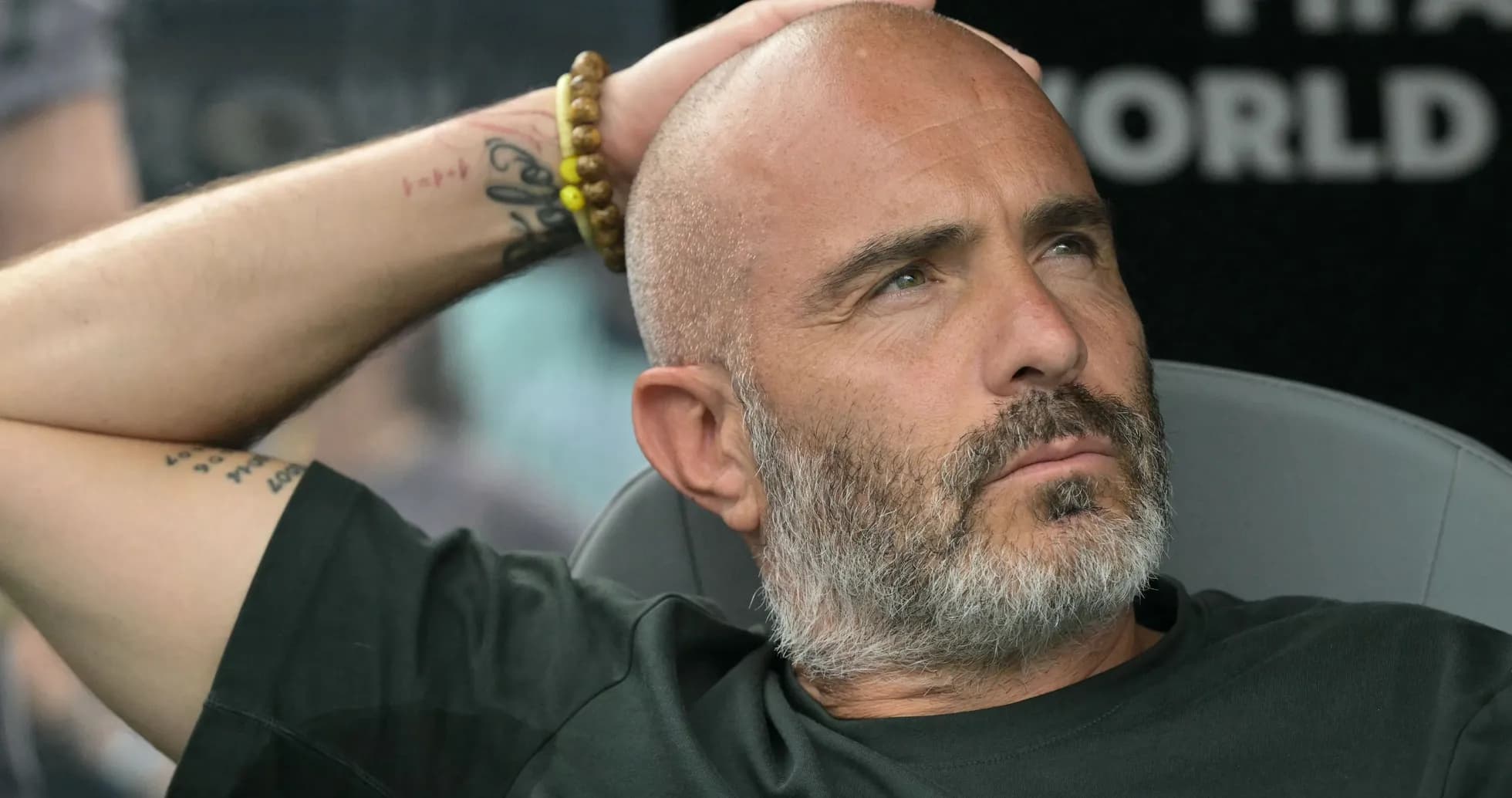 Coach seated, hand on head, during match