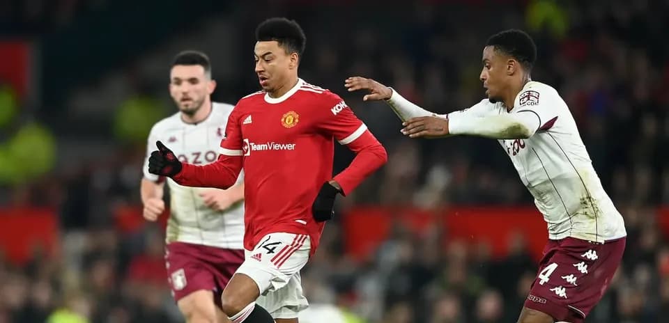 Manchester United player dribbling past Aston Villa defenders