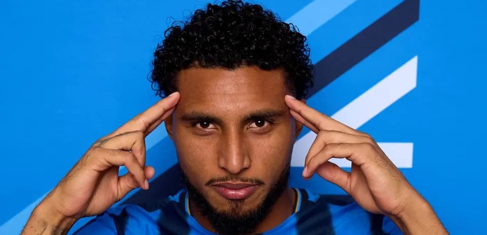Player posing with hands on temples against blue backdrop