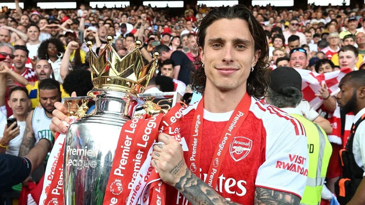 Player holding Premier League trophy with fans celebrating
