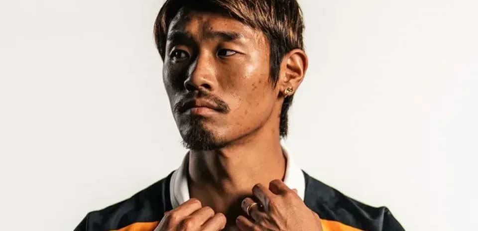 Athlete posing in team jersey against plain background