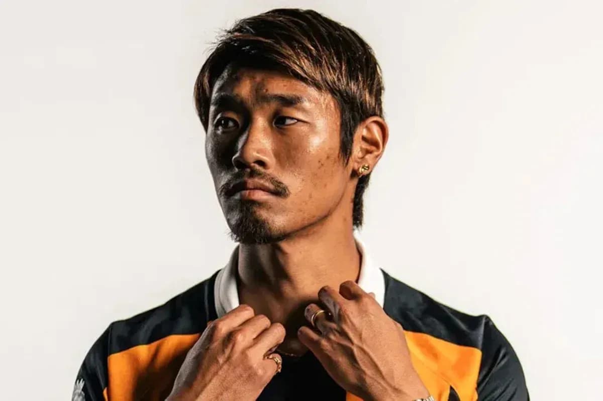 Athlete posing in team jersey against plain background
